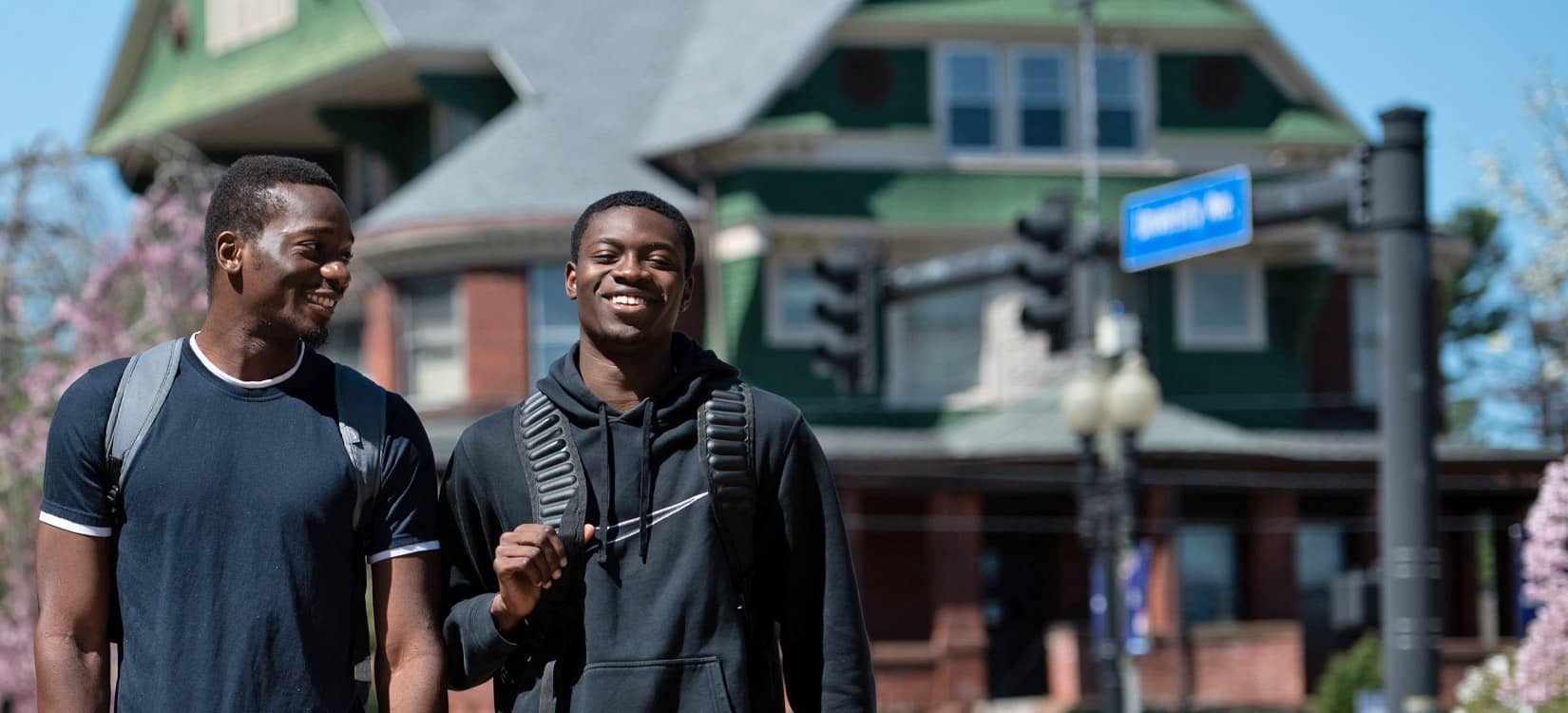 2 UB students laughing and walking on campus