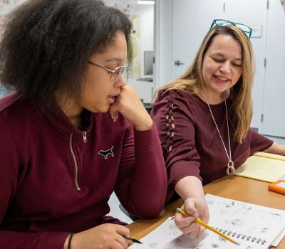 A student and mentor looking at a sketchbook