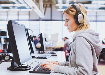 UB English Language Institute student on a computer with headphones