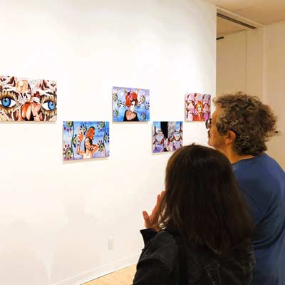 two people looking at art hung on a gallery wall