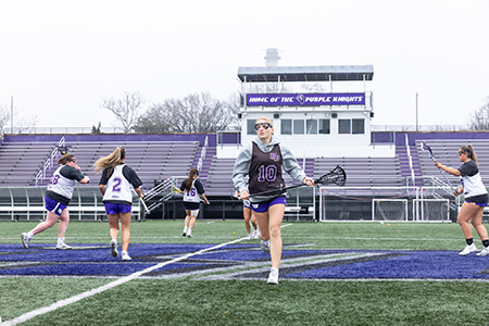 A UB student Lacrosse player warms up on the field with her teammates